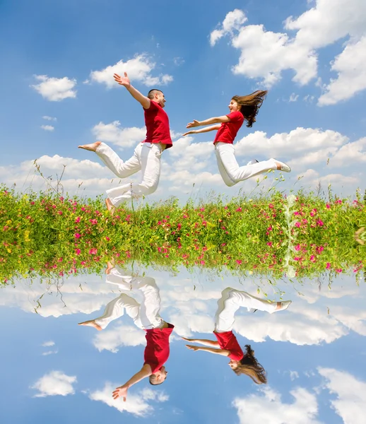 Happy Young Couple - l "équipe saute dans le ciel au-dessus d'un moi vert — Photo