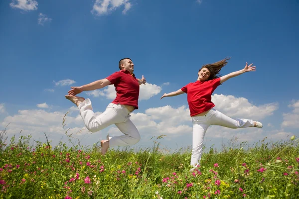 Щаслива молода закохана пара стрибає під блакитним небом — стокове фото