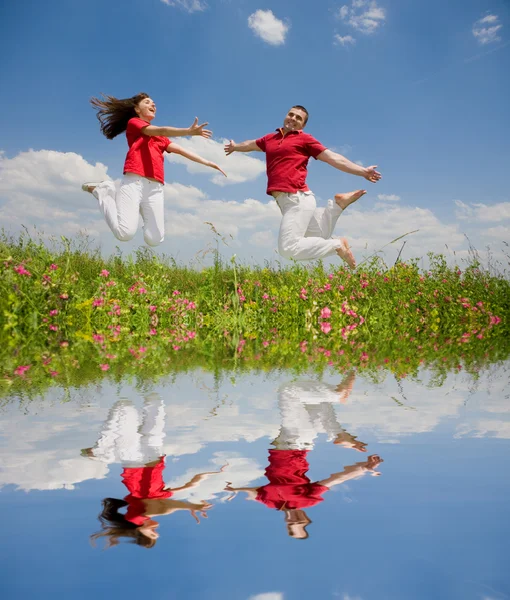 Pár šťastné mladé lásky - skákání pod modrou oblohou — Stock fotografie