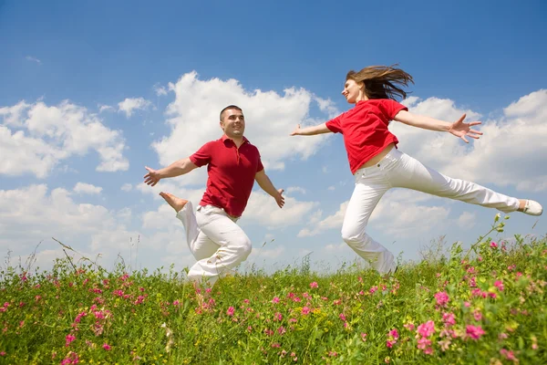 Mutlu genç aşk çift - mavi gökyüzü altında atlama — Stok fotoğraf