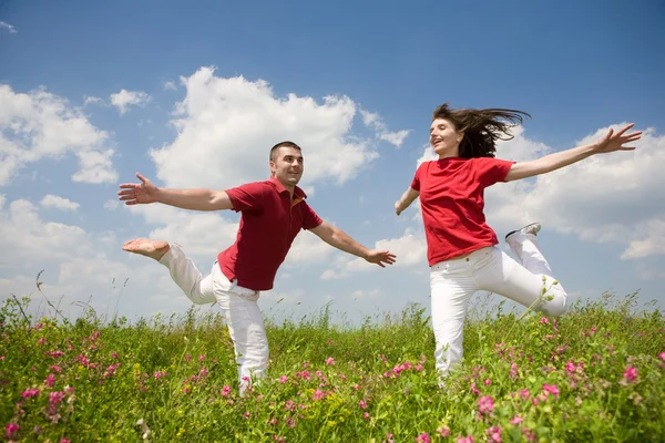 Happy Young love Couple - jumping under blue sky — Stock Photo, Image