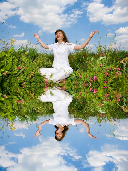 Jonge vrouw in witte kleren zitten in veld. — Stockfoto