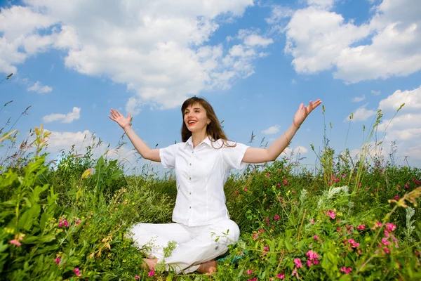 Young woman in white clothes sitting in field. — Stock Photo, Image