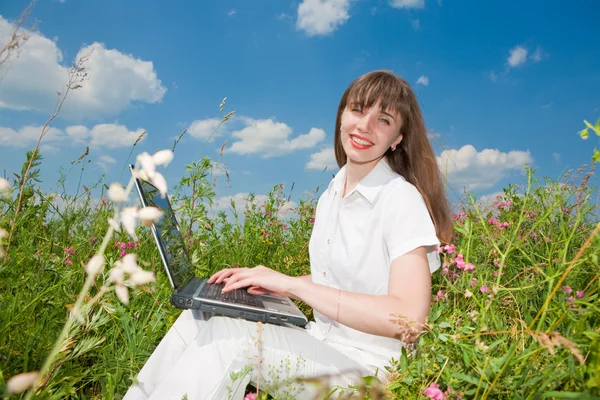 Jeune femme heureuse sur le champ d'herbe avec un ordinateur portable — Photo