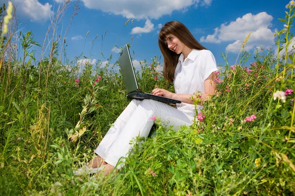 Jonge vrouw op het grasveld met een laptop — Stockfoto