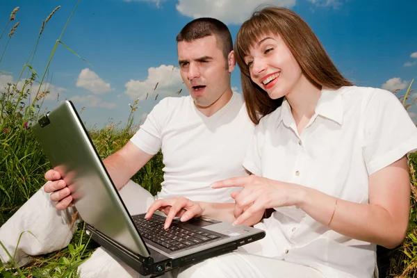 Casual feliz pareja en un ordenador portátil al aire libre —  Fotos de Stock