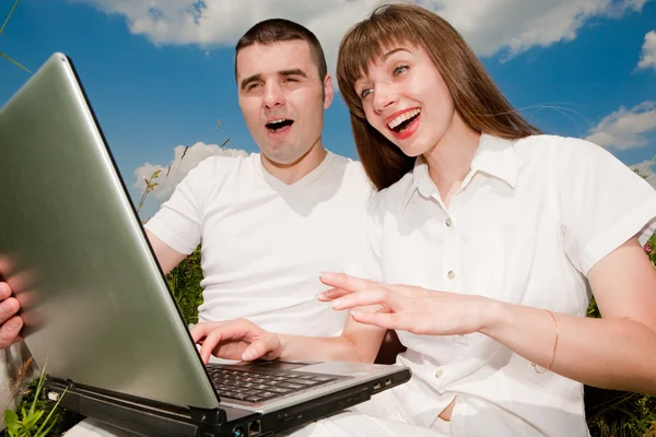 Casual gelukkige paar op een laptopcomputer buitenshuis — Stockfoto