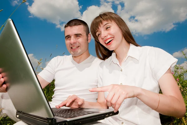 Casual casal feliz em um computador portátil ao ar livre — Fotografia de Stock