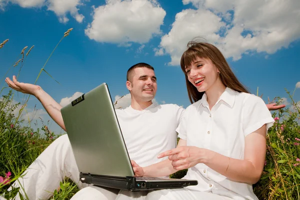 Casual casal feliz em um computador portátil ao ar livre — Fotografia de Stock