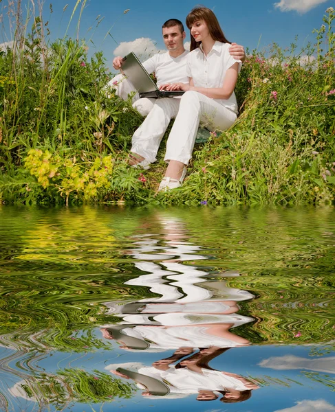 Příležitostné šťastný pár na notebooku venku. odráží v — Stock fotografie