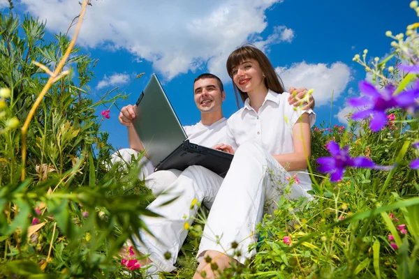 Bir Dizüstü Bilgisayar Ile Çim Sahada Oturan Genç Bir Çift — Stok fotoğraf