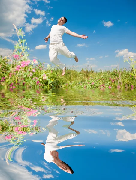 Šťastný mladý muž - skákání. odráží ve vodě — Stock fotografie