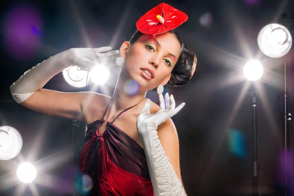 Beautiful girl with a red flower and in white gloves. On a background light shines — Stock Photo, Image