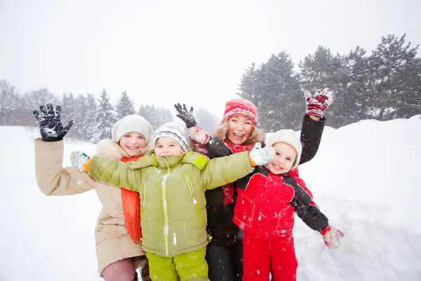 Portrait of happy mother and children together in snow on a cold — Stock Photo, Image
