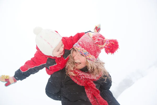 Porträtt lycklig mor och barn tillsammans i snö skrattar, smil — Stockfoto
