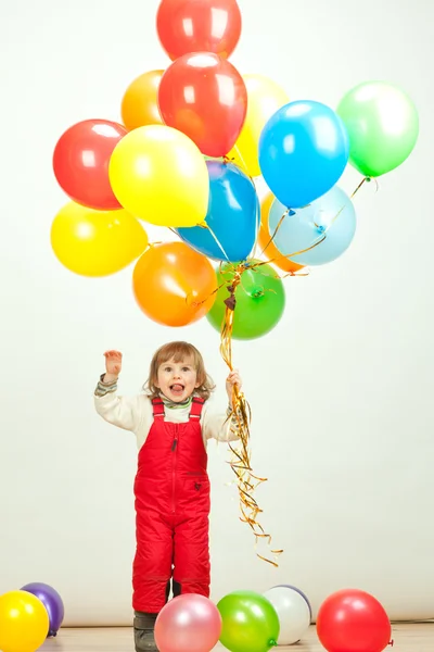 Klein meisje in de rode springen met ballonnen — Stockfoto