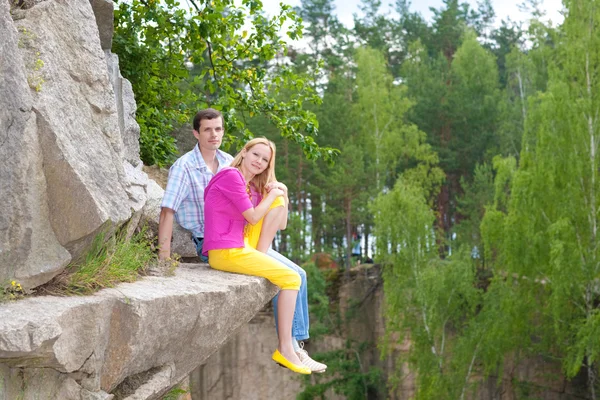 Casual feliz pareja se sienta en una roca — Foto de Stock