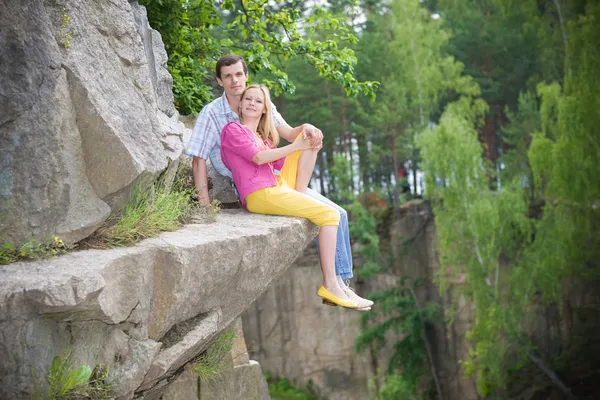 カジュアルな幸せなカップルは岩の上に座っています — ストック写真