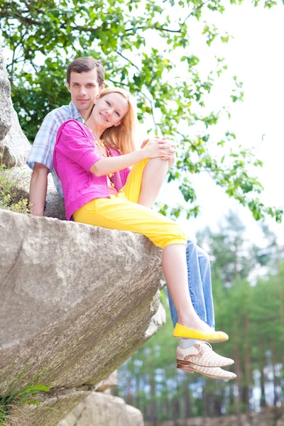 Casual happy couple sits on a rock — Stock Photo, Image