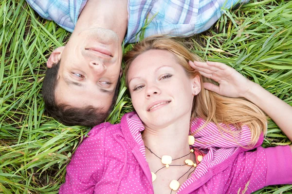 Молода пара кохання лежала на зеленій траві на відкритому повітрі . — стокове фото
