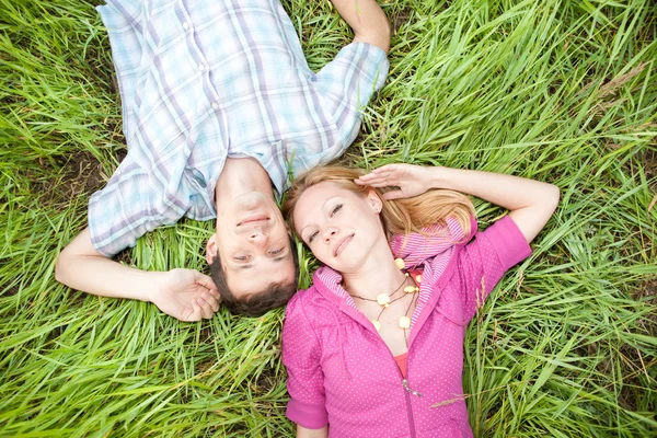 Młody miłość para lay na zielonej trawie na zewnątrz. — Zdjęcie stockowe