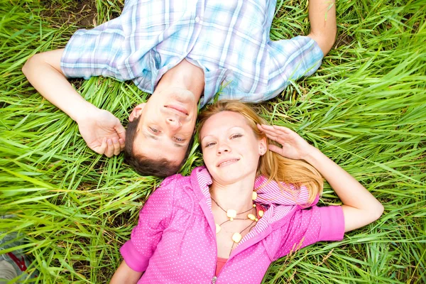 stock image Young love couple lay on the green grass outdoors