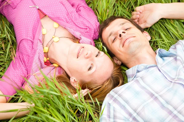 年轻的爱情侣躺在户外的绿草上 — 图库照片