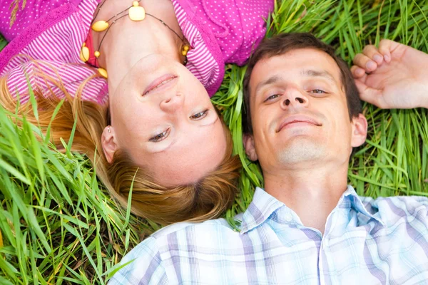 年轻的爱情侣躺在户外的绿草上 — 图库照片