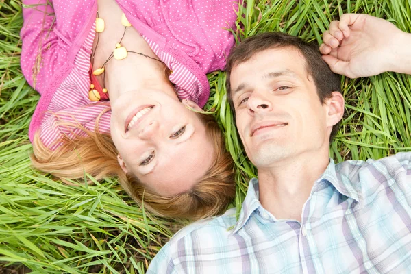 Giovane coppia d'amore giaceva sull'erba verde all'aperto . — Foto Stock