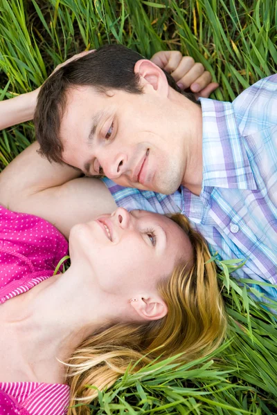 Jonge liefde paar lag op het groene gras buitenshuis. — Stockfoto