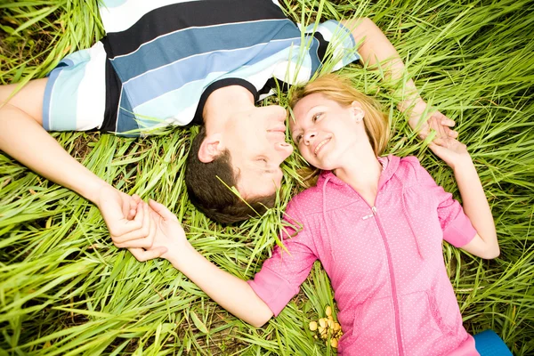 Jovem casal amor colocar na grama verde ao ar livre — Fotografia de Stock