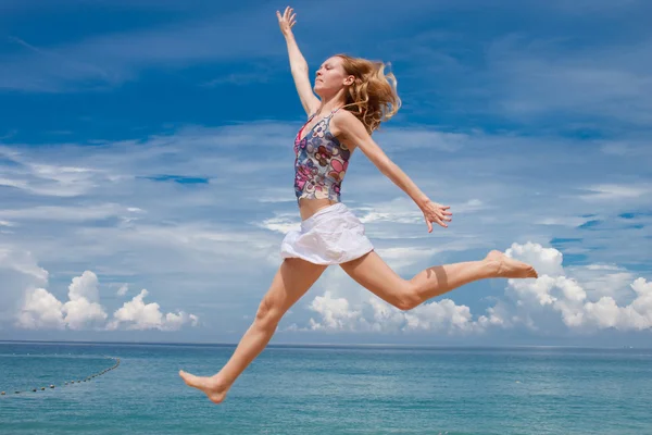 Happy young woman jumping on the background of the azure sea — Stock Photo, Image