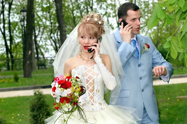 Bride and groom talk by phones — Stock Photo, Image