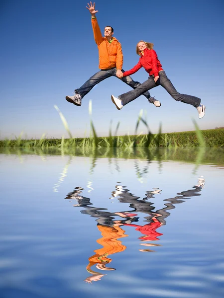 Счастливая Молодая Пара Прыгающая Небо Над Зеленым Лугом — стоковое фото