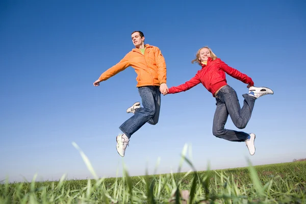 Щаслива усміхнена пара стрибає в блакитному небі — стокове фото