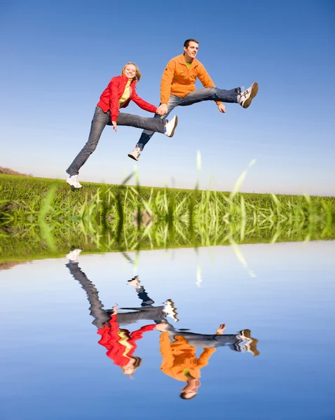 Щаслива усміхнена пара стрибає в блакитному небі — стокове фото