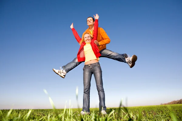 Joyeux couple souriant sautant dans le ciel bleu — Photo