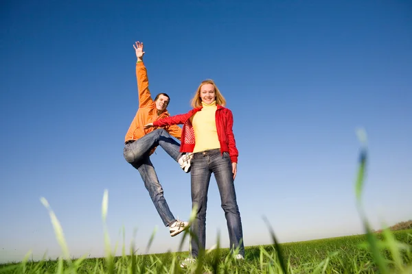 Lyckligt leende par hoppa i blå himmel — Stockfoto