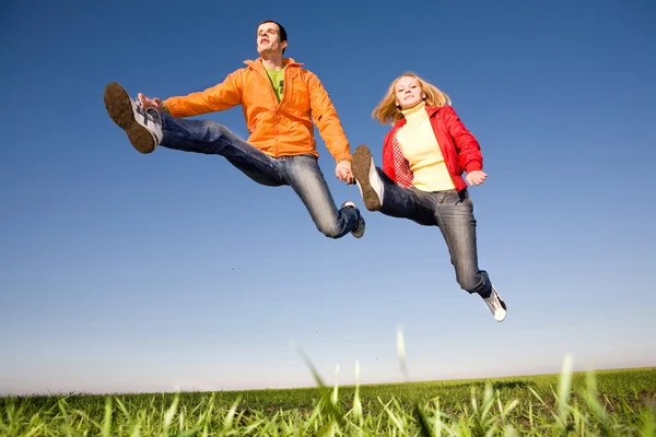青い空で跳んで幸せな笑みを浮かべてカップル — ストック写真