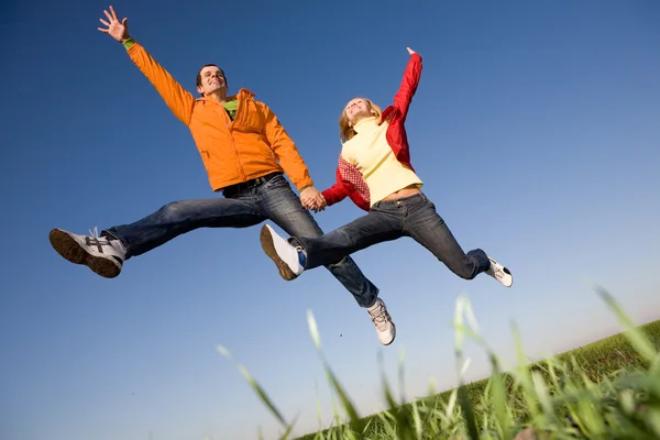 Feliz casal sorrindo pulando no céu azul — Fotografia de Stock