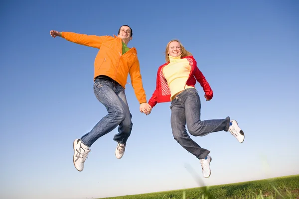 Felice giovane coppia che salta nel cielo — Foto Stock