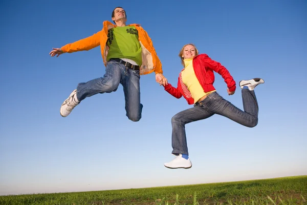 Happy smiling couple jumping in blue sky — Stock Photo, Image