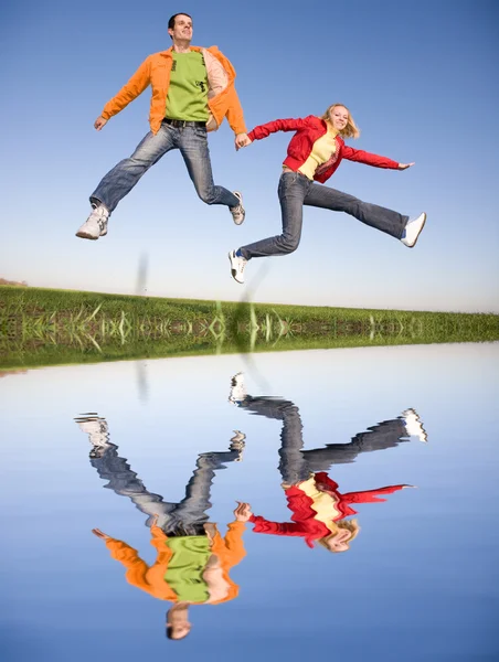 Glücklich lächelndes Paar springt in blauen Himmel — Stockfoto