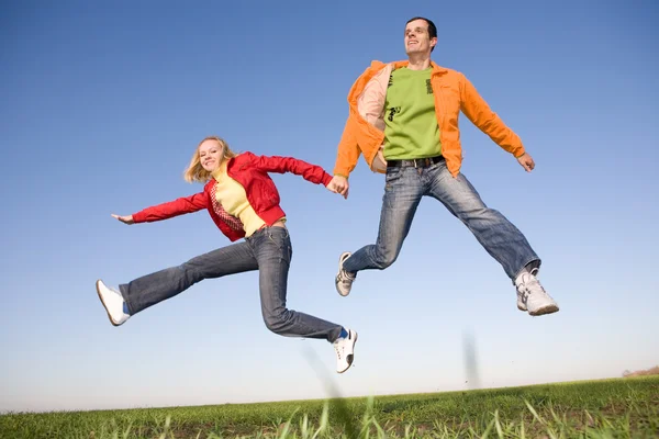 青い空で跳んで幸せな笑みを浮かべてカップル — ストック写真