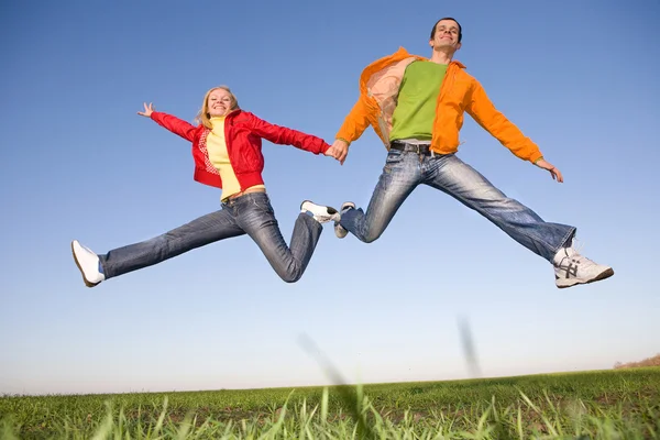 Feliz pareja sonriente saltando en el cielo azul — Foto de Stock