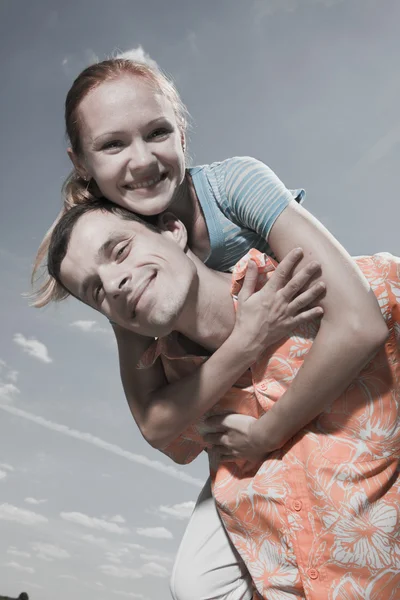 Jonge liefde paar glimlachend onder de blauwe hemel — Stockfoto