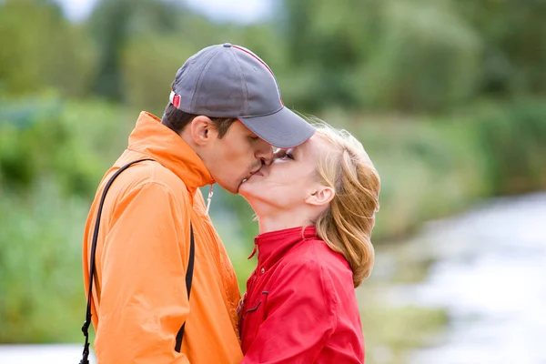Jonge liefde paar kuste op kust van rivier — Stockfoto