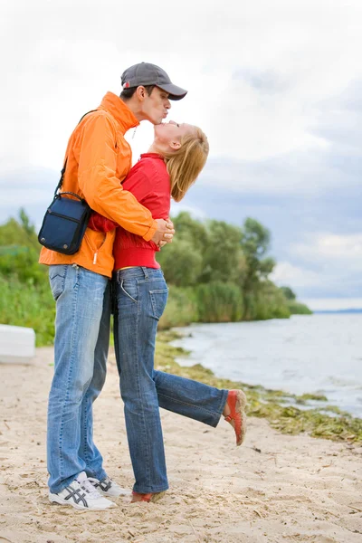 年轻爱的情侣亲吻了在海岸的河. — 图库照片