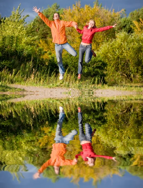 快乐的年轻夫妇 绿树的高空跳跃 — 图库照片