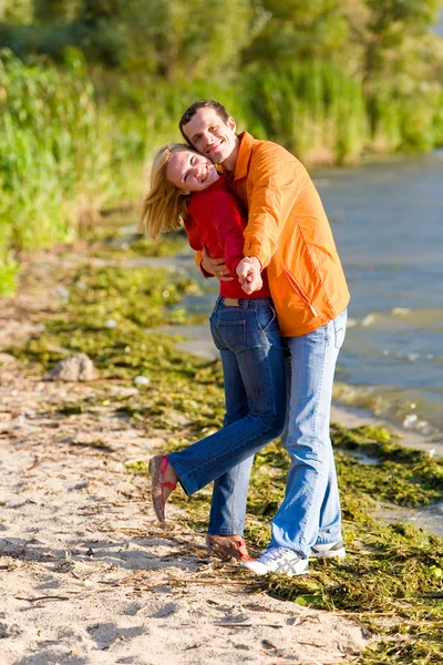 Junges Liebespaar umarmt sich am Ufer des Flusses — Stockfoto